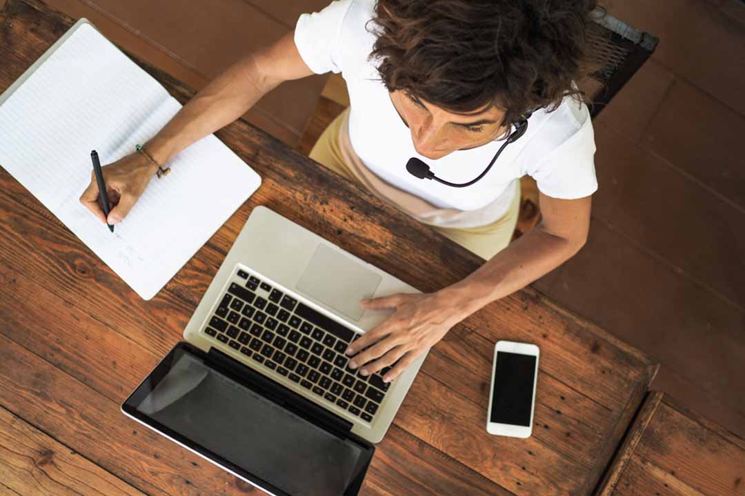 Working on a laptop at a desk wearing a headset.