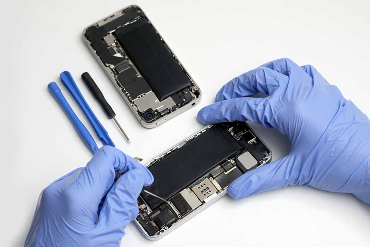 Gloved hands working to repair a device.