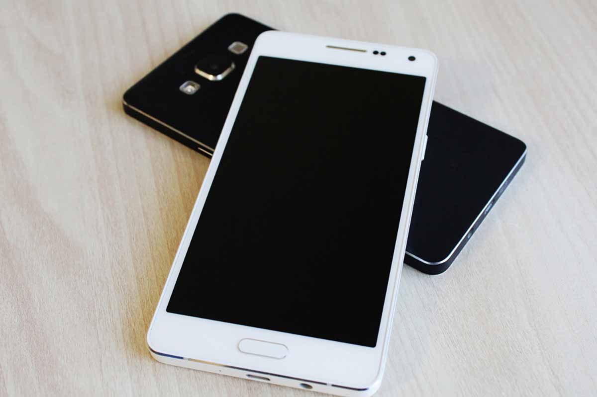 Cell phones stacked on a table.