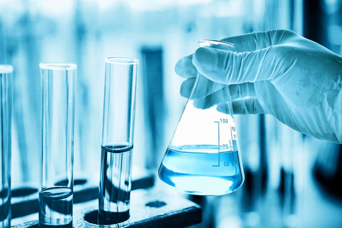 Scientist holds a beaker with solution in a lab.