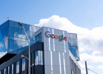 Google sign on company building with blue sky and clouds above.