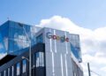 Google sign on company building with blue sky and clouds above.