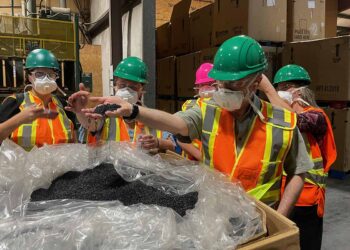 Employees of KC Recycling handle PP pellets the company has processed.