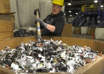 Worker at an e-scrap facility raking shredded material.