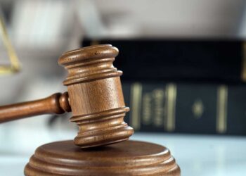 Court gavel on desk with books in background.