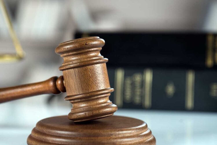 Court gavel on desk with books in background.