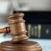 Court gavel on desk with books in background.
