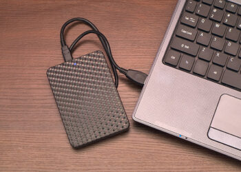 An external hard-drive and laptop on a desk.